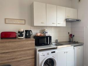 a kitchen with a washing machine and a microwave at Studio Cosy avec Terrasse - Gare a 2min & wifi in Compiègne