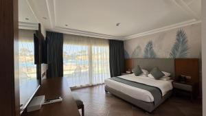 a bedroom with a bed and a desk and a window at Grand Ocean Sokhna Hotel & Resort in Ain Sokhna