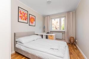 een witte slaapkamer met een bed en een raam bij Frida by Grand Apartments in Gdańsk