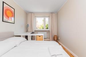 een wit bed in een kamer met een raam bij Frida by Grand Apartments in Gdańsk