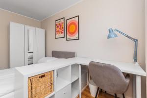 een wit bureau met een stoel en een lamp bij Frida by Grand Apartments in Gdańsk