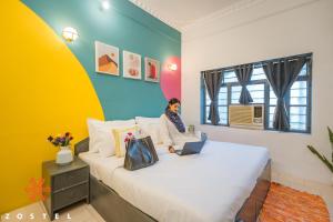 Una mujer sentada en una cama en una habitación. en Zostel Pushkar, en Pushkar