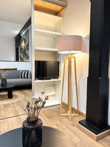 a living room with a television and a table with a lamp at L'Alcôve - Centre-ville - Moderne & Cosy - Commerces à Proximité in Obernai