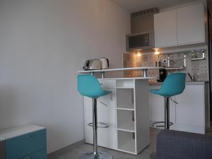a kitchen with two blue chairs and a counter at La Grande Motte by la Paillère in La Grande Motte