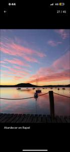 a sunset over a lake with boats in the water at Alojamiento Punta verde Gran casa orilla Lago Rapel piscina ,jardines ,quincho ,terrazas,para 13 in Las Cabras