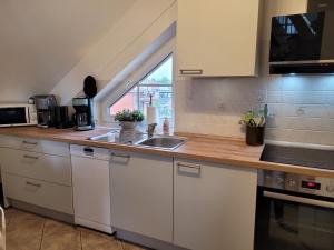 a kitchen with white cabinets and a sink and a window at Fewo Büsum in Büsum