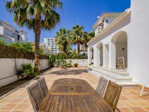 ein Holztisch und Stühle auf einer Terrasse mit Palmen in der Unterkunft Cubo's Villa La Butibamba in La Cala de Mijas