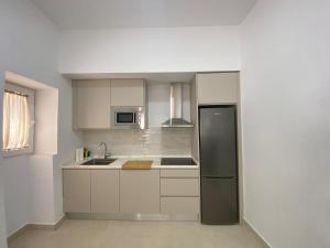 Una cocina con gabinetes blancos y un refrigerador negro. en Sol Sherry, en Jerez de la Frontera