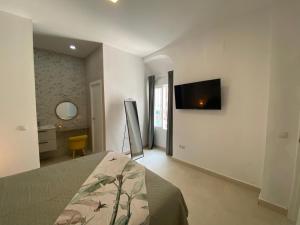 Un dormitorio con una cama y un televisor en la pared. en Sol Sherry, en Jerez de la Frontera