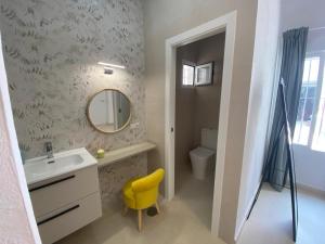 Un baño con un lavabo, un espejo y una silla amarilla. en Sol Sherry, en Jerez de la Frontera