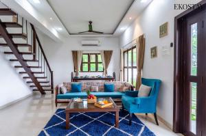 a living room with blue couches and a table at EKOSTAY Luxe - Oceanic Villa in Alibaug