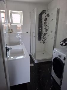 a white bathroom with a shower and a sink at Sunshine apartments in Karlobag +15 photos