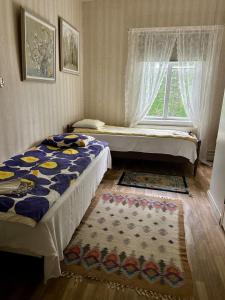 two beds in a room with a window and a rug at Atmoshperic countryside house in Vehmaa