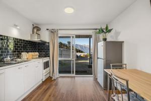 a kitchen with a table and a refrigerator at Arawata Retreat - Queenstown Mountain Serenity in Queenstown