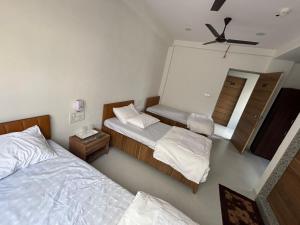 a bedroom with two beds and a ceiling fan at Hotel VEDANT in Surat
