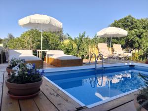 a swimming pool with two umbrellas and chairs and a pool at B&B Luxury Villa Olimpia in Selva di Fasano