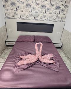 a bed with a pink ribbon on top of it at Casa Elena in Constanţa