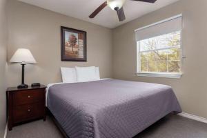 a bedroom with a bed with a ceiling fan and a window at Eagle's Den Three Rivers Texas a Travelodge by Wyndham in Three Rivers