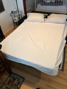 a large bed with white sheets and pillows at Traversier Gratuit- Aux Trois Filles in Lévis +10 photos