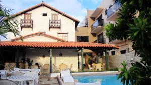 a villa with a swimming pool in front of a building at Pousada Canto da Baleia in Arraial do Cabo