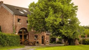 a brick house with a tree in front of it at La Source de Manon - Gite à Houyet, en Ardennes in Houyet