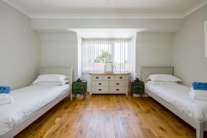 two beds in a room with wooden floors and a window at Candle Island View - Superb Harbour Views from Three Floors in Poole
