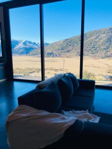 a living room with a couch and a large window at El filo del Lolog in San Martín de los Andes