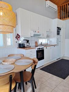 a kitchen with white cabinets and a table and chairs at Metsätuuli 4 in Kalajoki