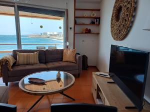a living room with a couch and a tv at Sobre el Mar by CanariApartment, Oceanfront House with 3 Balconies in Salinetas in Telde