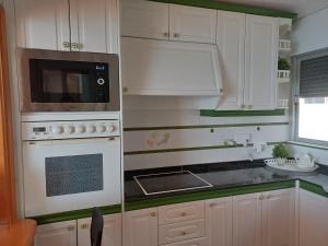cocina con armarios blancos, microondas y fogones en Salinetas VISTAMAR, en Telde 39 fotos más