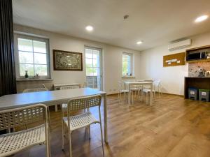 a dining room with tables and chairs and windows at Kulpe Guest Rooms in Domantai