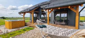 a house with a hammock and a gazebo at Osada Miłojeż - całoroczne Domy Premium w Borach Tucholskich, Jacuzzi pod gwiazdami in Gostycyn