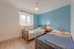 deux lits dans une chambre aux murs bleus dans l'établissement Location meublé Ty Kim, à Le Folgoët