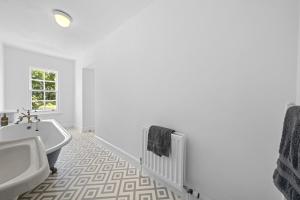 une salle de bain blanche avec une baignoire et un lavabo dans l'établissement Mackinnon Cottage - 3 bedroom Cottage, à Broadford 37 autres photos