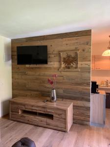 Una sala de estar con un televisor en una pared de madera. en Prime Studio, en Leutasch