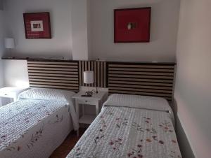 a bedroom with two beds and a nightstand with two lamps at Chillout La Rioja in Haro