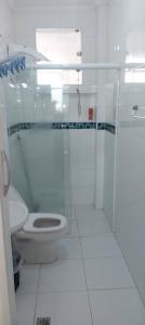 a white bathroom with a toilet and a shower at Kitão PÉ na Areia in São Vicente
