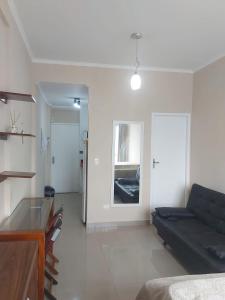 a living room with a black couch and a table at Kitão PÉ na Areia in São Vicente