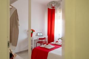a room with a bed with a desk and a red curtain at Shalacory in Riposto