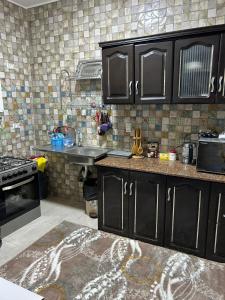 una cucina con armadi neri e lavandino di كمبوند روضة زايد قلب الشيخ زايد a Sheikh Zayed