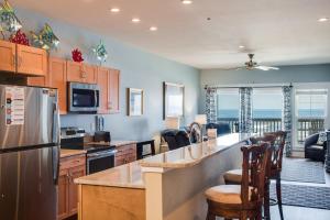 a kitchen with a refrigerator and a counter with chairs at Star of the Sea in Kill Devil Hills