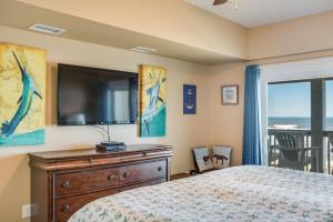 a bedroom with a tv and a bed with a dresser at Star of the Sea in Kill Devil Hills