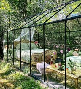 a glass greenhouse with a bed and a table at Logements Insolites, Les Rêves d'Ambre 