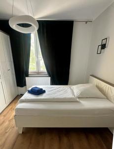 a bedroom with a white bed with a black curtain at Teatralna Nowoczesny Apartament Centrum Bolesławca in Bolesławiec