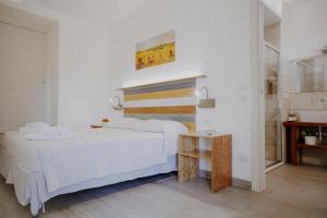 a white bedroom with a bed and a table at Le Vie di Feronia in Terracina