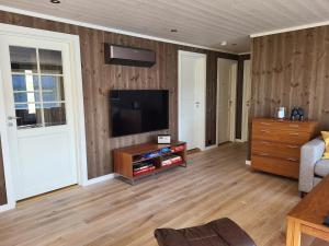 a living room with a flat screen tv on a wooden wall at Hytte ved sjøen in Røyra