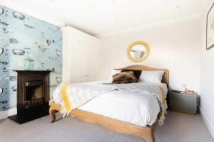 a white bedroom with a bed and a fireplace at The Midsummer Common - Modern & Spacious 2BDR House with Garden in Cambridge