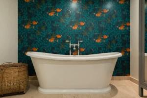 a white bath tub in a bathroom with a blue wall at The Midsummer Common - Modern & Spacious 2BDR House with Garden in Cambridge