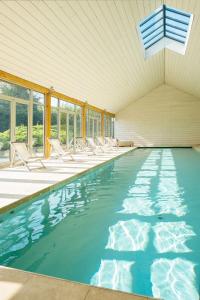 a swimming pool with chairs in a room with windows at The Garden House in Bath