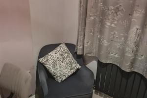 a pillow sitting on a chair next to a curtain at 1 Bed Sleeps 2 with Private Garden in Harlow